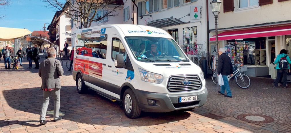 Flyerbild Bürgerbusse fit für die Zukunft Der Bürgerbus Kirchzarten fährt an einem sonnigen Tag durch den Ortskern.