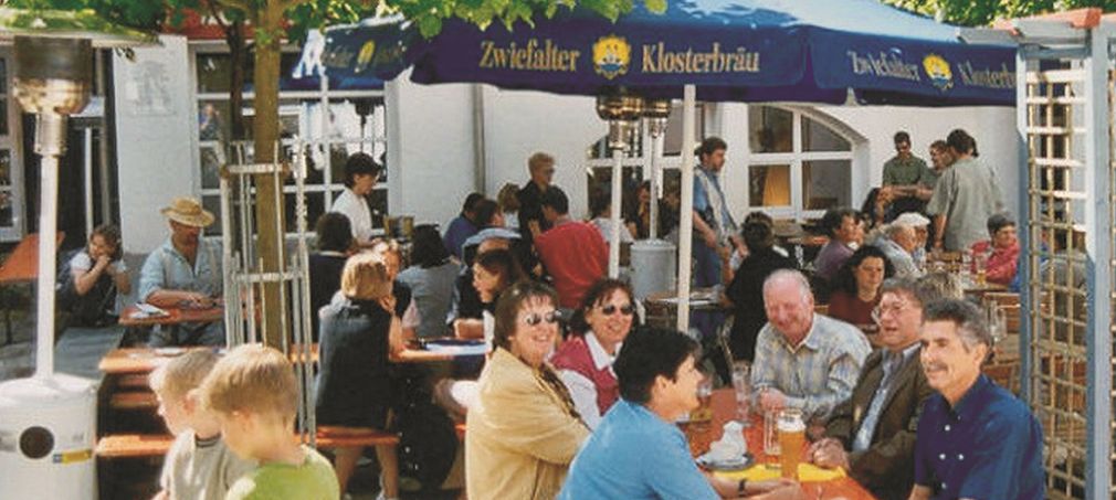 Flyerbild Feste feiern - aber sicher Personen an Biertischgarnitur unter einem Sonnenschirm
