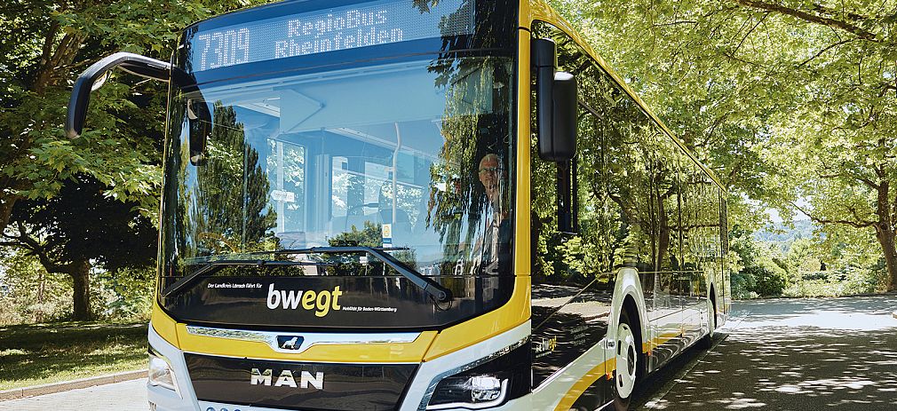 Flyerbild Gelber Linienbus befindet sich auf einer Straße unter Laubbäumen